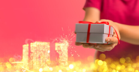 Woman s hands holding beautifully wrapped gifts Christmas gift box. Christmas and New Year lights....