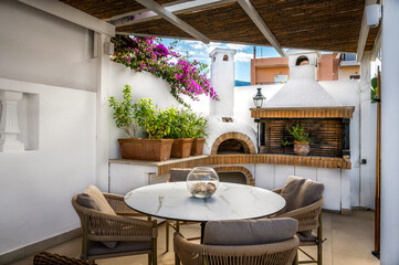 An idyllic open-air dining area unfolds with a tastefully arranged table and chairs, accompanied by...