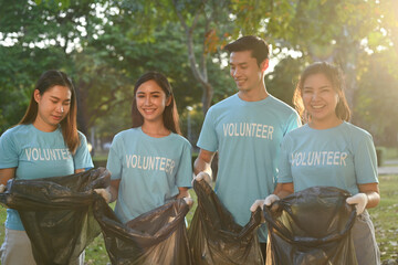 Team of young volunteers with garbage bags cleaning up the forest together
