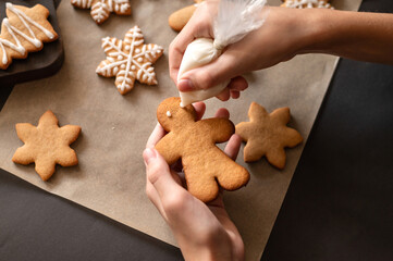 Making decoration of gingerbread man cookie from piping bag with sugar glaze