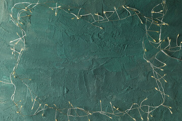 Garland with yellow lights on green background, space for text