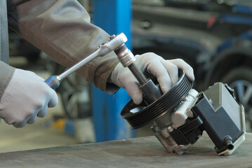 Car repair at a car service center. Dismantling the pulley of the power steering pump. - obrazy, fototapety, plakaty