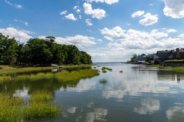 Fototapeta na wymiar View over the tranquil water of Smith Cove in Greenwich, CT, USA with view towards the Long Island sound and large cumulus clouds in blue sky reflected in water