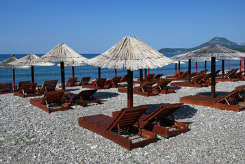 Bar, Montenegro, Dalmatia, Balkans, Europe - 09.2023 : shingle beach, sun loungers, parasols,  blue...