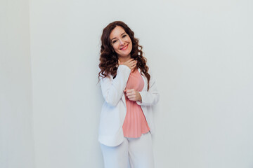 Beautiful brunette woman in white suit posing in bright studio