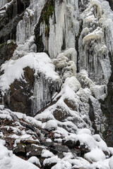 Fototapeta na wymiar Anstelle des herabfallenden Wassers hängen hier nun Eiszapfen herab und der Fels ist teilweise mit Schnee bedeckt. Weihnachtsstimmung am Harzer Wasserfall
