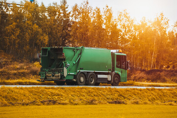 Recycling truck rides on the road in the suburbs. Garbage pickup truck. Concept of sorting garbage for a better sustainable future. - obrazy, fototapety, plakaty
