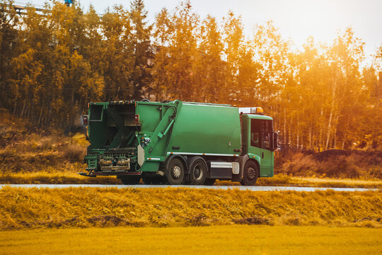 Recycling truck rides on the road in the suburbs. Garbage pickup truck. Concept of sorting garbage for a better sustainable future.