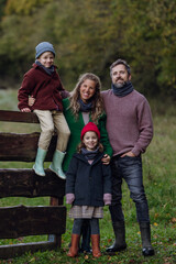 Portrait of family outdoors going on walk in nature. Mother, father and kids spending time outdoors during cold autumn day.