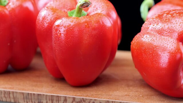 Fresh red peppers on wooden chopping board, close-up pan
