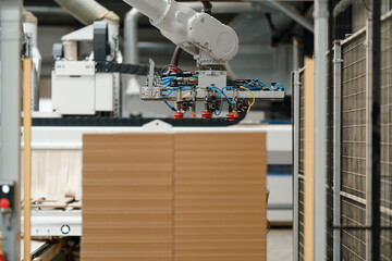Naklejka premium Close up of robotic arm in modern industrial factory, production of wooden furniture. Big furniture manufacturing facility with robotics and automation.