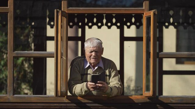Elderly man arranging his white hair while having a phone video call with loved ones