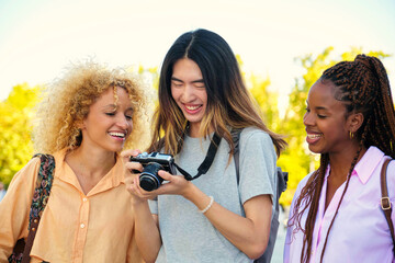 Three multiracial friends looking at the photos in a camera while sightseeing in Madrid, Spain.