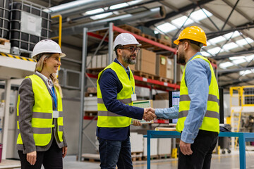 Engineers shaking hands with project manager in modern industrial factory, talking about new...