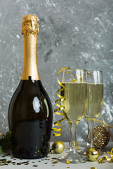 Champagne bottle with confetti, glasses and christmas decor on colored holiday background. Flat lay New Year decorations