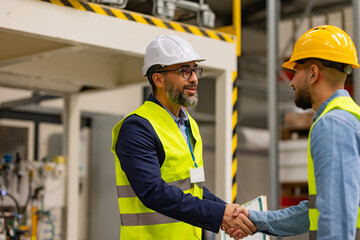 Engineer shaking hands with project manager in modern industrial factory, talking about new production project. Team management in manufacturing facility. - obrazy, fototapety, plakaty