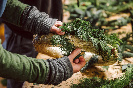 H&auml;nde halten Draht und Adventskranz. Mensch bastelt einen weihnachtlichen Adventskranz.