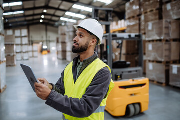Warehouseman with tablet checking delivery, stock in warehouse. Warehouse manager using warehouse management software, app.