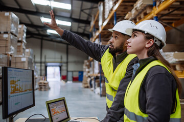 Warehouse manager talking with logistics employee in warehouse, planning transport of products, talking shipping process. - obrazy, fototapety, plakaty