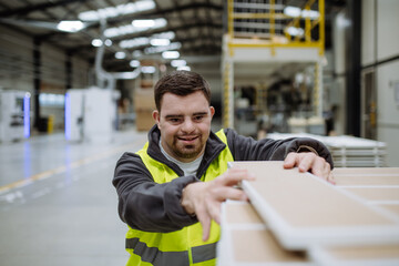 Portrait of young man with Down syndrome working in warehouse. Concept of workers with...