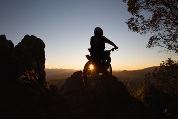 Man with motocross bike against beautiful lights, silhouette of a man with motocross motorcycle On...