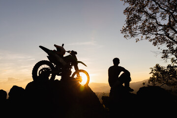 Man with motocross bike against beautiful lights, silhouette of a man with motocross motorcycle On...