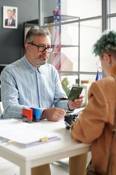 Vertical image of mature manager of visa center working with client in office