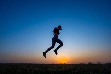 A happy child jumps with vitality under the blue sky at sunset. just from a young woman jumping in nature while doing sports