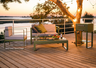 place to relax at sunset with a metal sofa and two armchairs with fabric cushions, a table with food