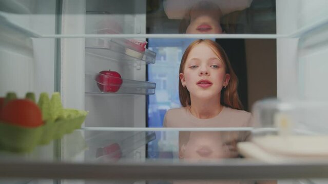 Young Girl Opening Fridge Door and Looking at Empty Shelves. Kid Feeling Hungry and Selecting Healthy Food and Products to Shop. Pretty Child Choosing Grocery Ingredients of Refrigerator to Cook Meal