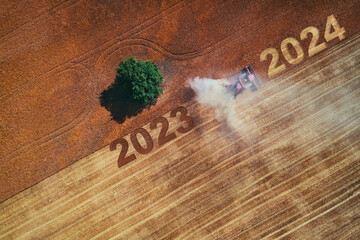 2024 Happy new year concept of aerial view on the combine working on the large wheat field - 687896030
