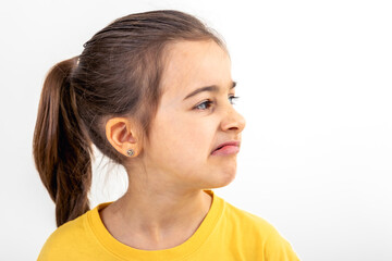 A little girl grimaces with displeasure on a white background, isolated. - obrazy, fototapety, plakaty