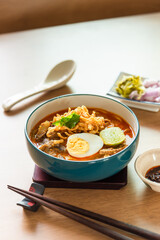 Northern Thai style curried noodle soup with beef and egg on wooden table