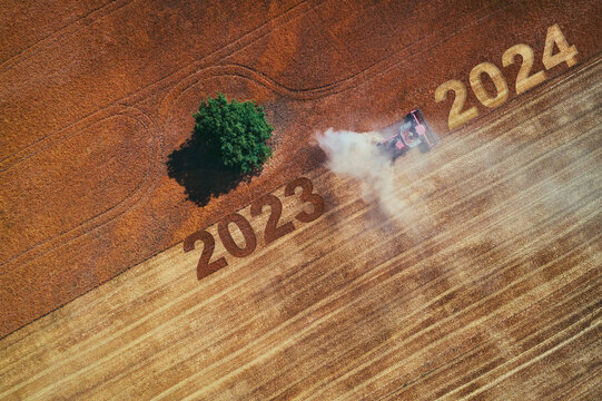 2024 Happy new year concept of aerial view on the combine working on the large wheat field