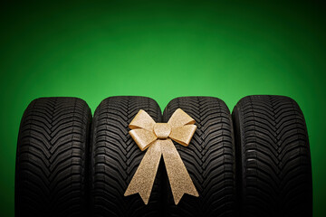 Car tires, new tyres, winter wheels isolated on green background with bow ribbon present.