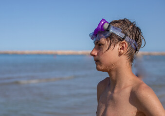 Teenager with a diving mask enjoys a carefree day, reflecting the happiness of a summer beach outing,side view.