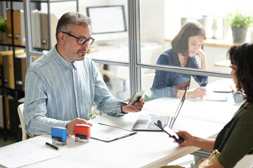 Manager of visa center having consultation with woman, he checking her documents at meeting in visa...