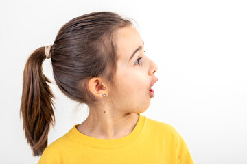 Little girl looks to the side in surprise on a white background isolated.