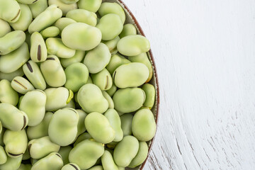 top view raw green broad beans on wooden table with copy space