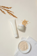 Flat lay of unlabeled jar and tube decorated with a handful of wheat seeds and wheat ears. A dish...