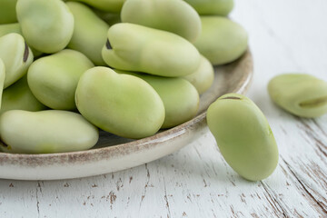 raw green broad beans on a wooden table