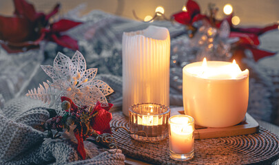 Cozy winter composition with burning candles and Christmas decor details.