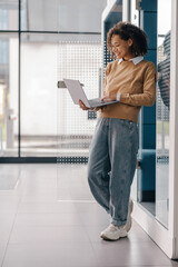 Stylish business woman using laptop while standing on modern office background