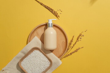 Square dish of rice placed on a scarf. Blank label pump bottle displayed on a wooden tray on yellow...
