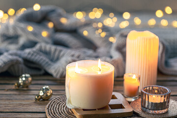 Cozy background with burning candles and knitted element.