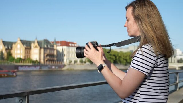 Woman takes picture at city street. Female traveler walks in city with camera