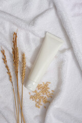 White towel decorated as a background with wheat ears, wheat seeds and unbranded tube displayed on....