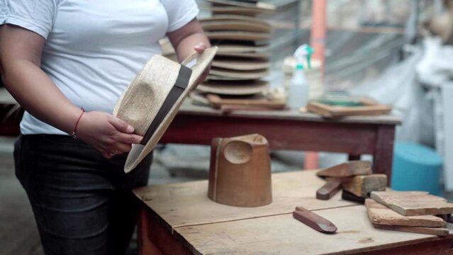 An adult Hispanic woman is decorating a natural fiber hat in a workshop. Concept of handmade traditional clothing