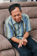 Elderly man experiences discomfort and pain in hands. Old man with finger pain, showcasing his actions of massaging his arthritic hand and wrist.