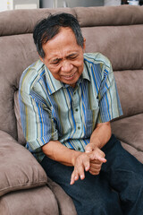 Fototapeta premium Elderly man experiences discomfort and pain in hands. Old man with finger pain, showcasing his actions of massaging his arthritic hand and wrist.